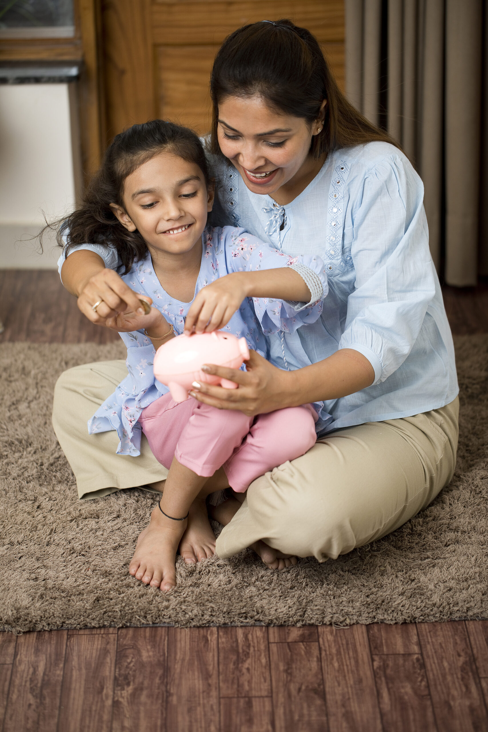 Mother and daughter saving money in piggy bank
